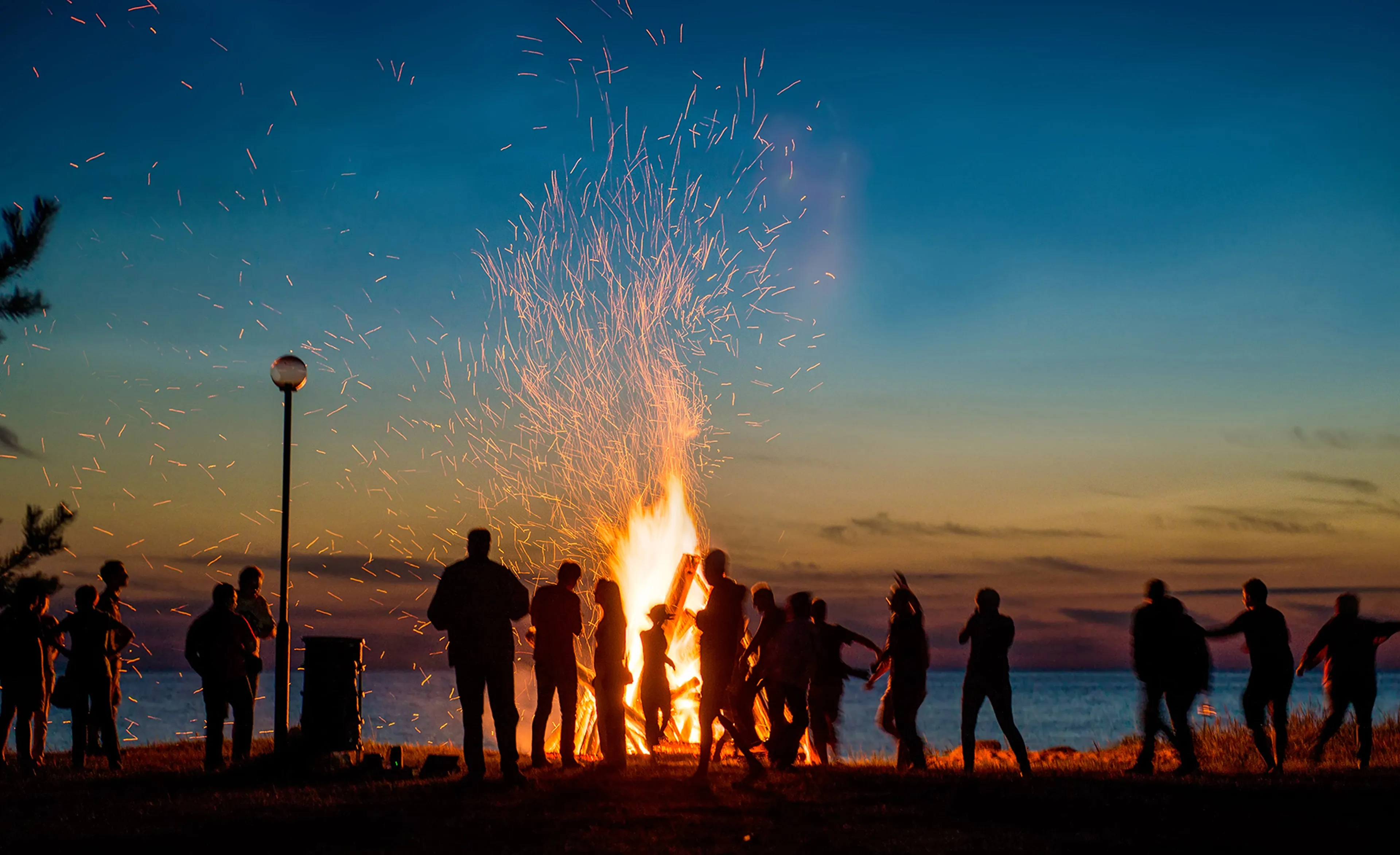Youth gathered around a bonfire at dusk