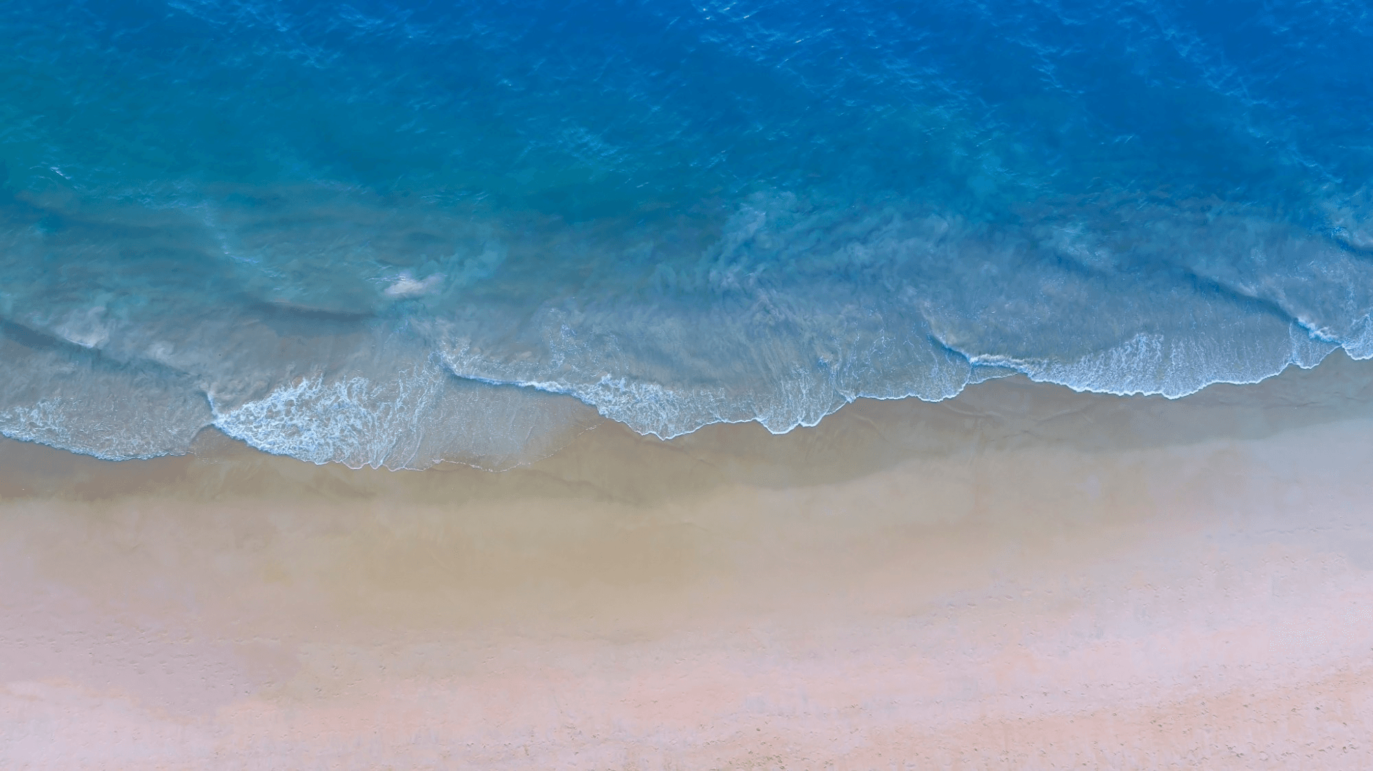 Aerial view of waves washing onto a sandy shore