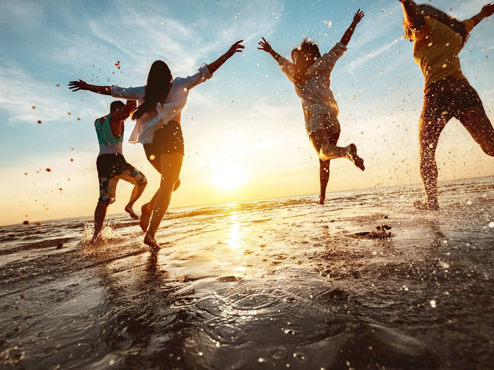 Students running and laughing together on the beach at sunset