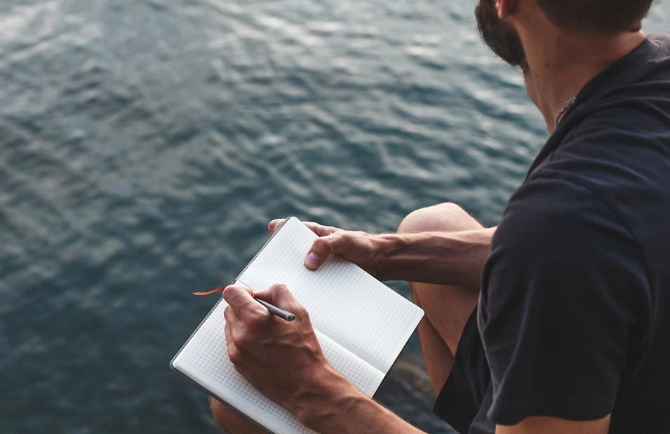 A student journaling by the water during a quiet moment