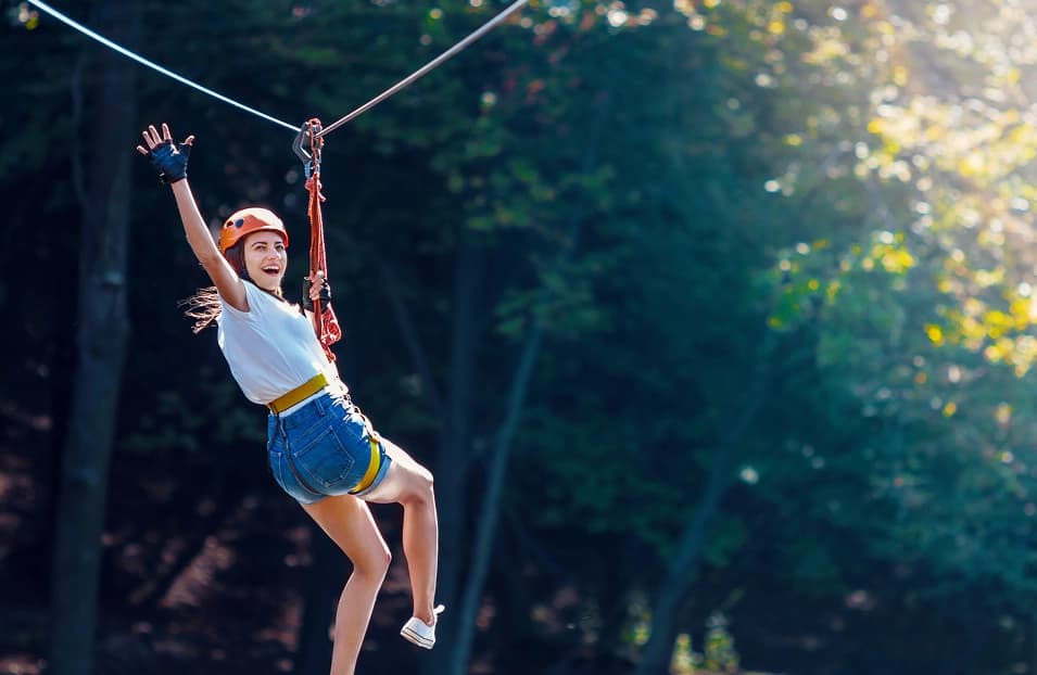 A student ziplining through the trees