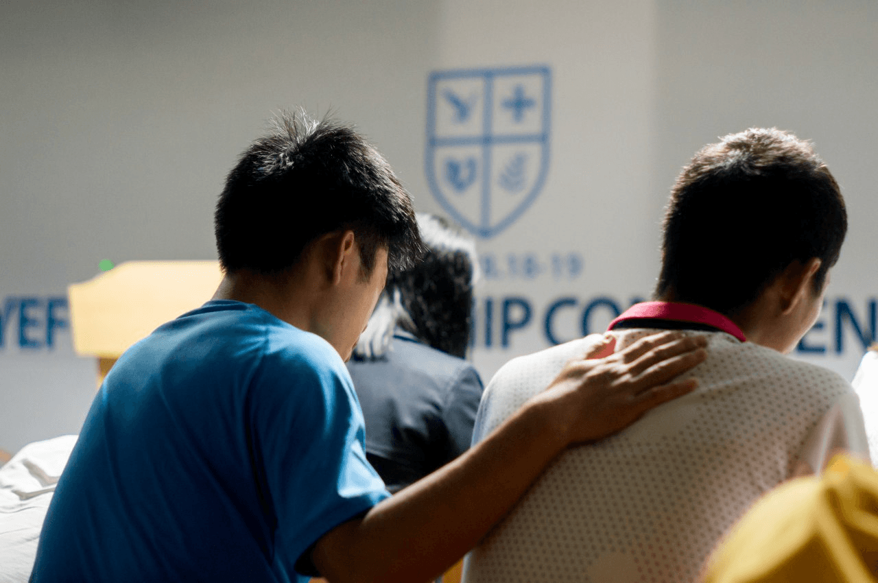 Two students praying together at a YEF fellowship conference