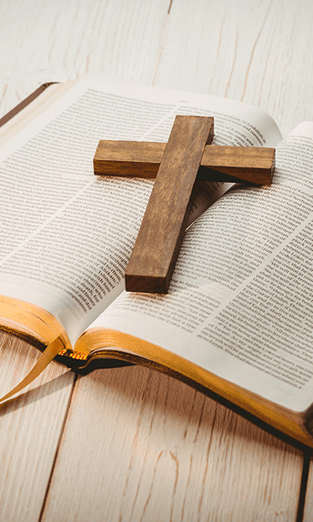 A wooden cross resting on an open Bible
