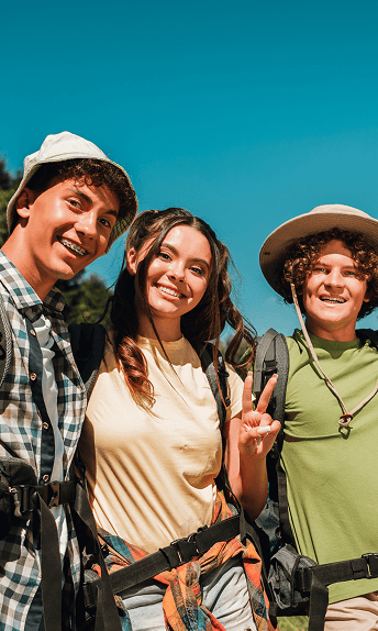 Three students smiling together outdoors on a mission trip